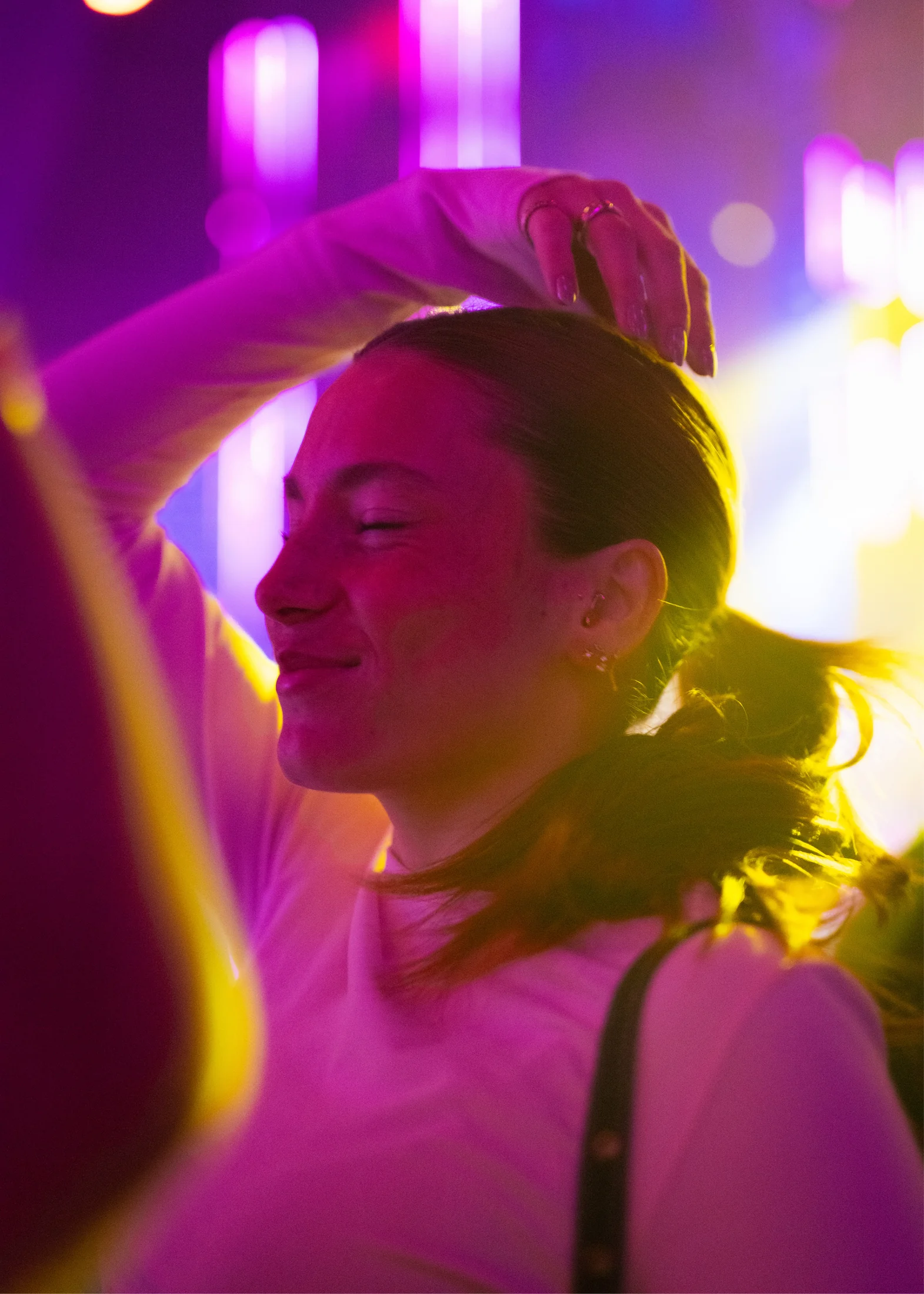 Festival guest wearing Alpine hearing protection under coloured lights